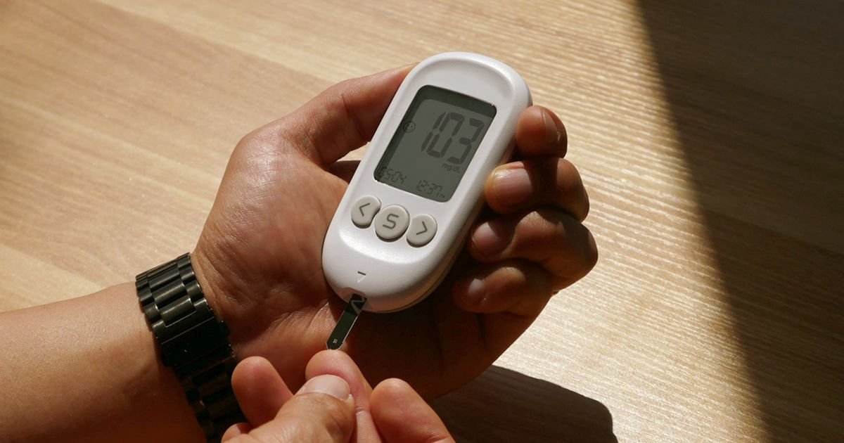 Mãos segurando um medidor de glicose com fita de teste